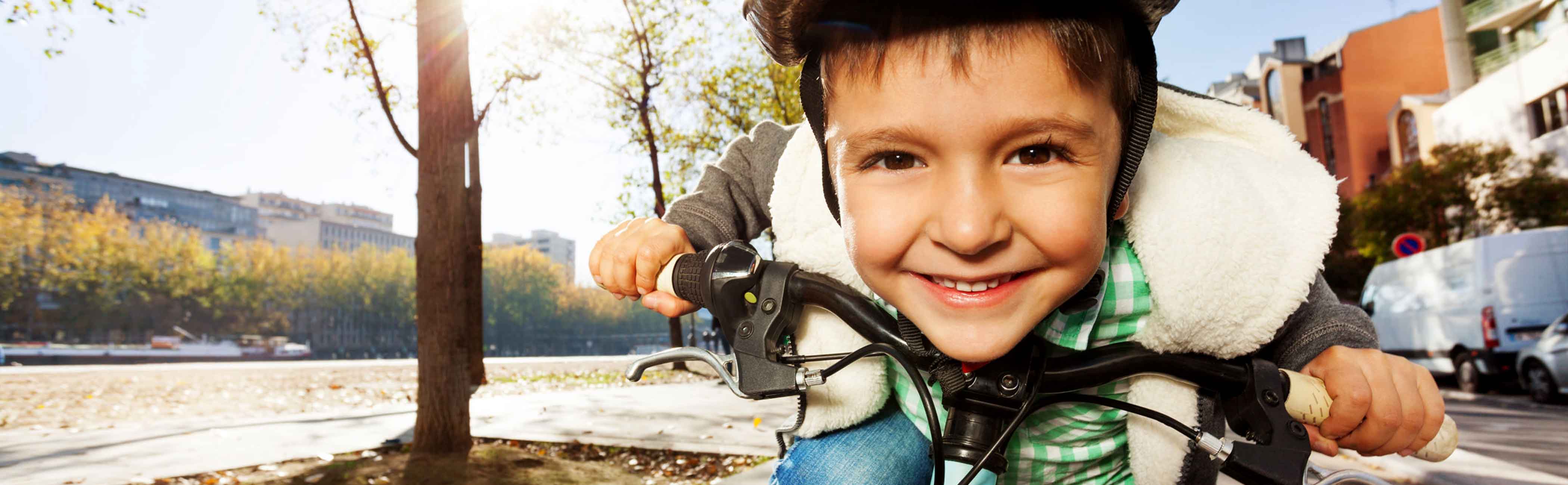A young boy smiling as he zooms on his bike.